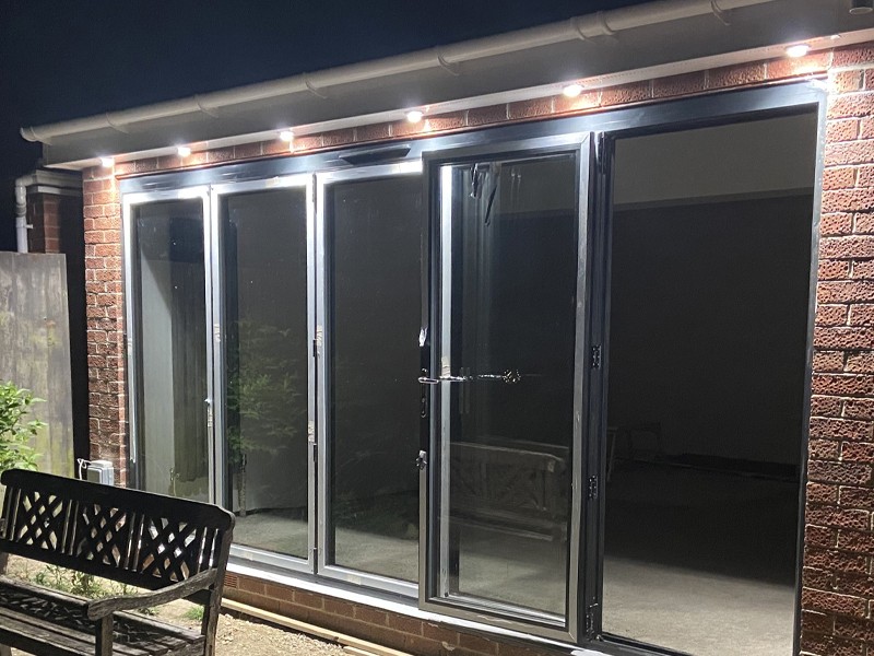 Exterior lighting across a rear elevation with bifold doors at night